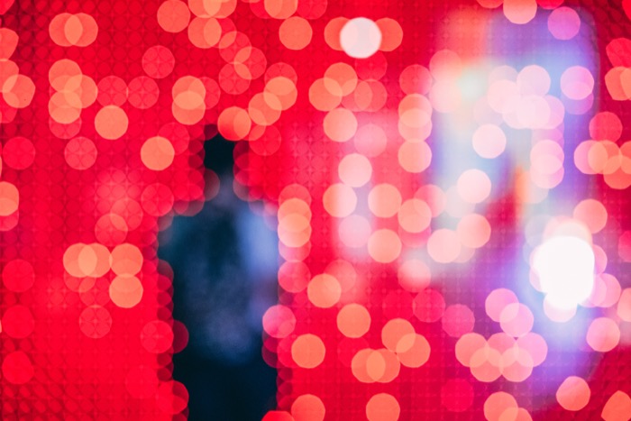 The outline of a person blurred by red lights.